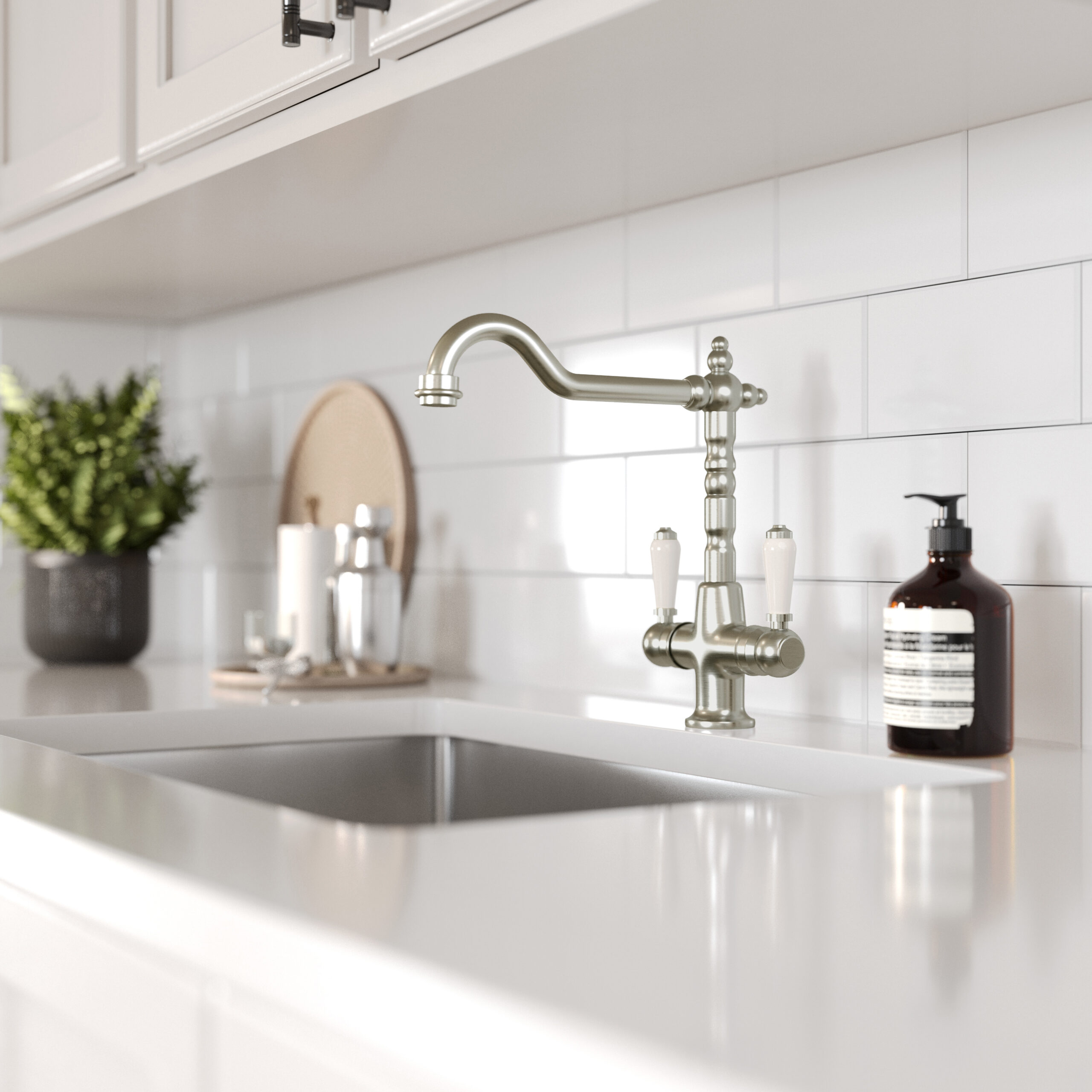Alma brushed chrome dual lever tap with white ceramic handles with a brushed chrome sink in a white kitchen